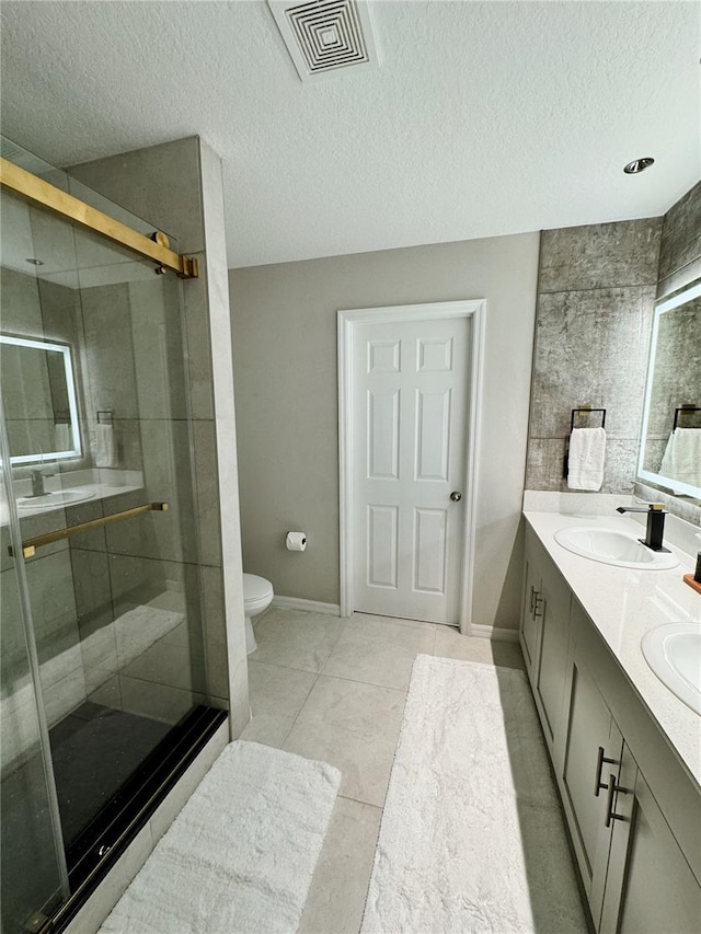 bathroom featuring tile patterned flooring, vanity, toilet, and a textured ceiling