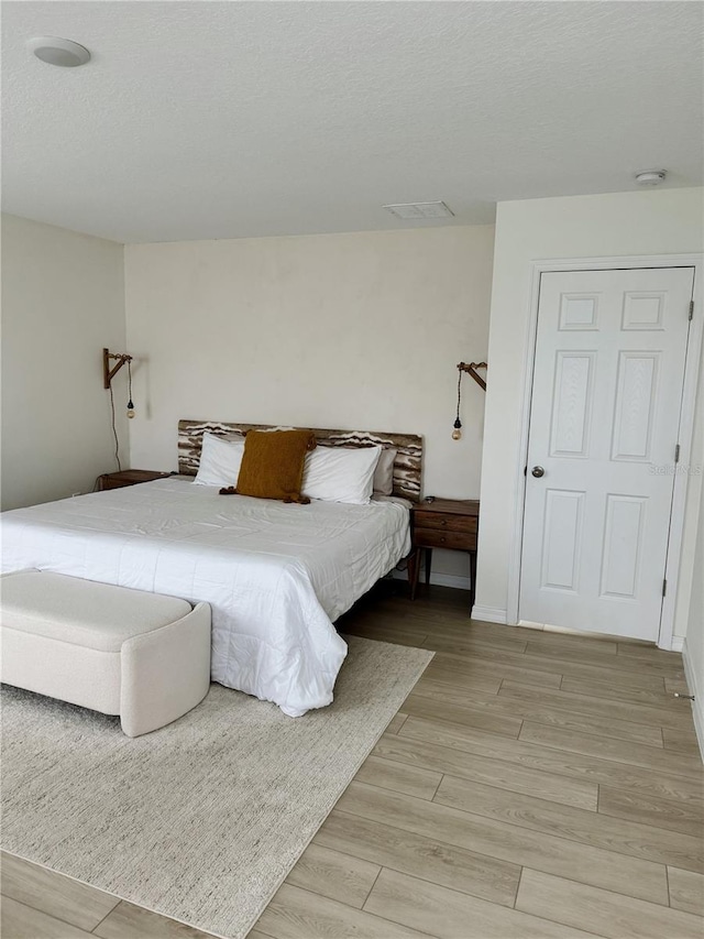 bedroom featuring light hardwood / wood-style flooring and a textured ceiling