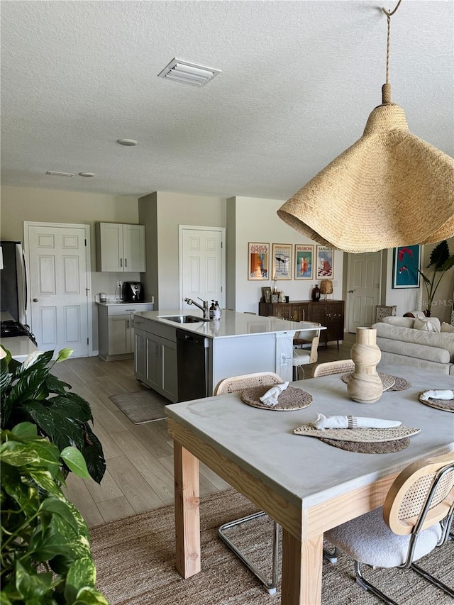 dining room with sink, a textured ceiling, and hardwood / wood-style flooring