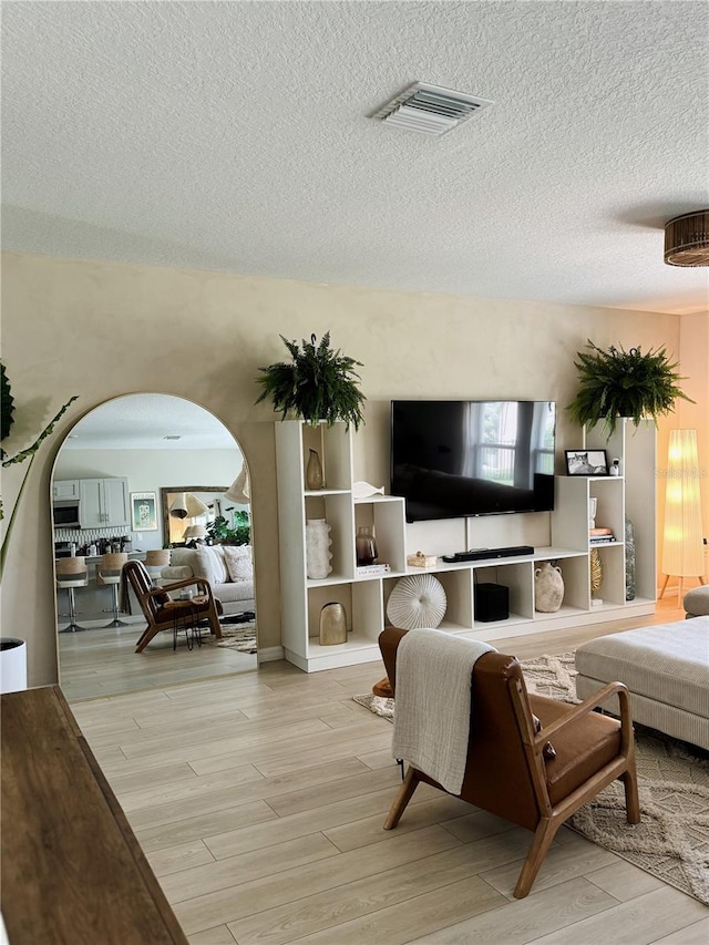 living room featuring light wood-type flooring and a textured ceiling