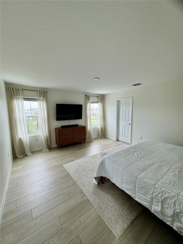 unfurnished bedroom with light hardwood / wood-style floors and a textured ceiling