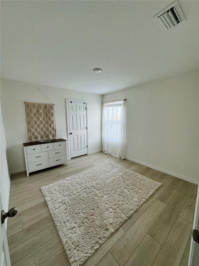 bedroom with a textured ceiling and light hardwood / wood-style floors