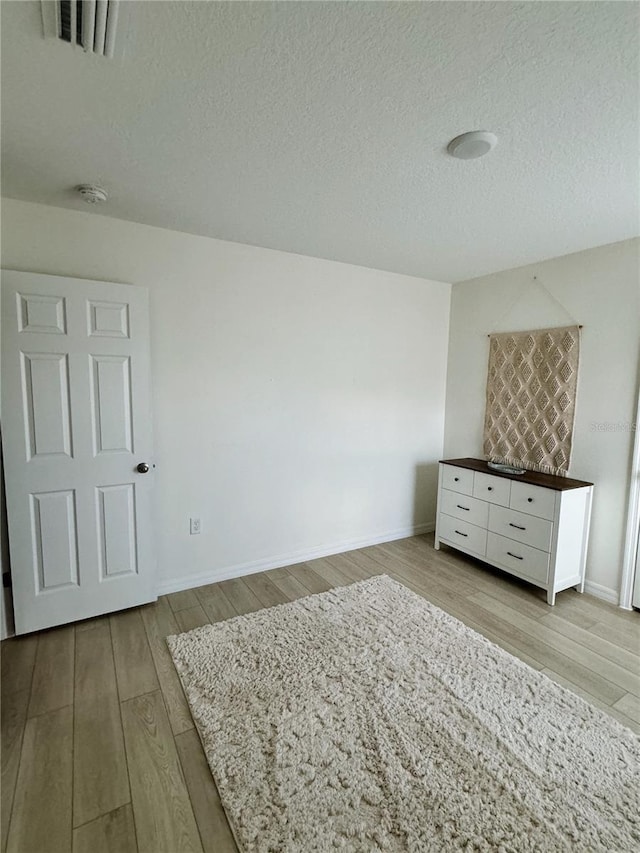 unfurnished bedroom featuring a textured ceiling and light wood-type flooring