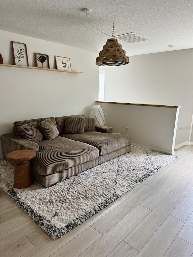 living room with light hardwood / wood-style floors and a textured ceiling