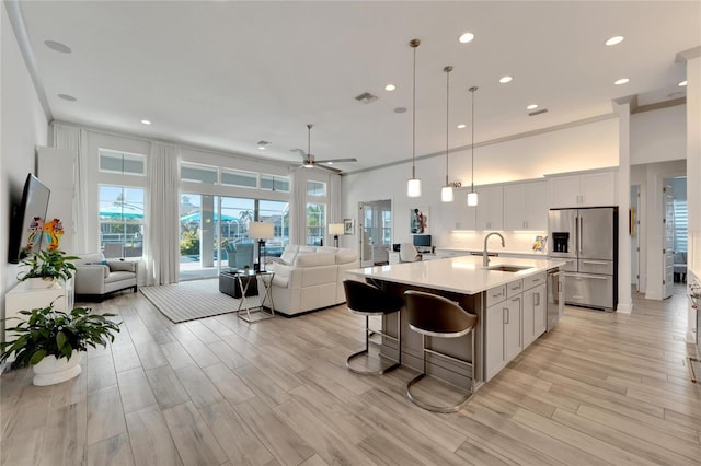 kitchen with decorative light fixtures, sink, white cabinetry, appliances with stainless steel finishes, and a kitchen breakfast bar