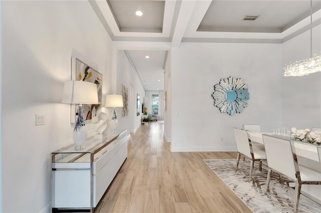 corridor with a raised ceiling and light hardwood / wood-style flooring