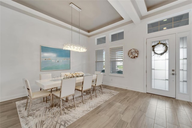 dining area featuring a chandelier, a raised ceiling, and a towering ceiling