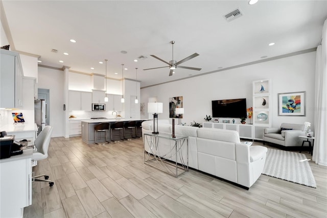 living room with ceiling fan and crown molding