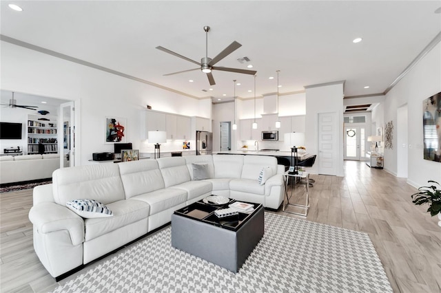 living room with ceiling fan, built in features, ornamental molding, and light hardwood / wood-style flooring