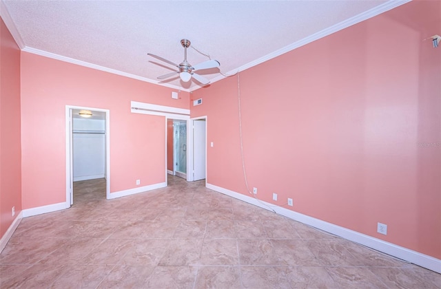 unfurnished bedroom featuring a walk in closet, a closet, ceiling fan, and ornamental molding