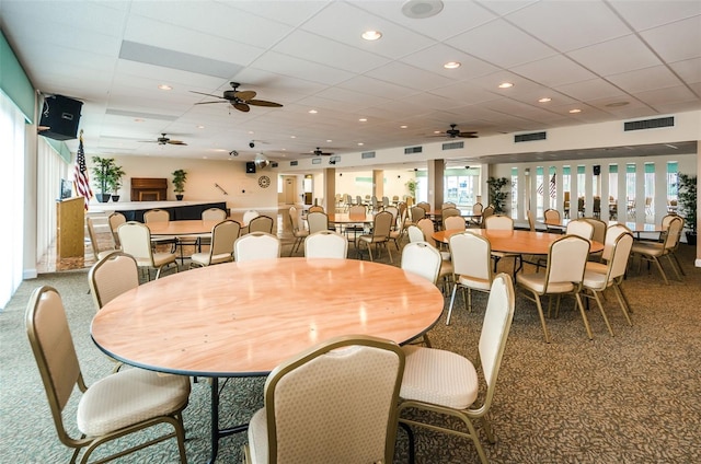 dining space featuring carpet flooring, a drop ceiling, and ceiling fan