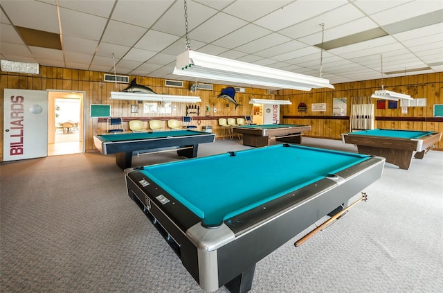 game room featuring carpet flooring, a paneled ceiling, and wood walls