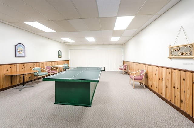 playroom with a paneled ceiling, wood walls, and carpet floors