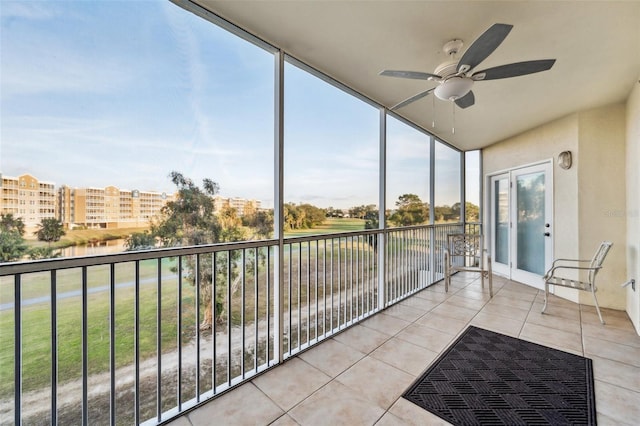 sunroom / solarium with ceiling fan and a water view