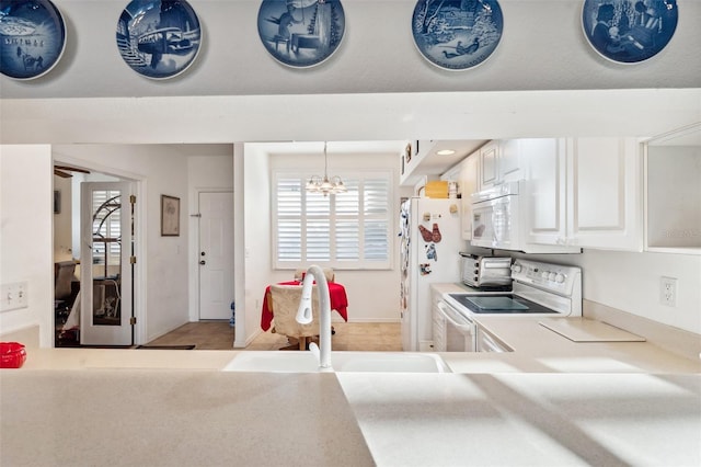 kitchen with white appliances, white cabinets, sink, hanging light fixtures, and a notable chandelier