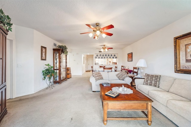 carpeted living room featuring a textured ceiling and ceiling fan