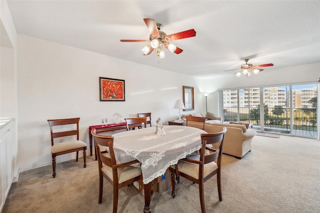 carpeted dining area with ceiling fan