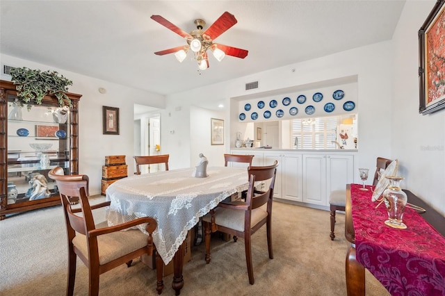 dining area featuring ceiling fan and light colored carpet