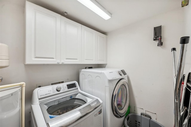 clothes washing area with cabinets and separate washer and dryer