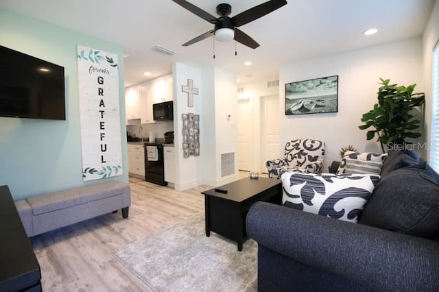 living room featuring ceiling fan and light hardwood / wood-style floors