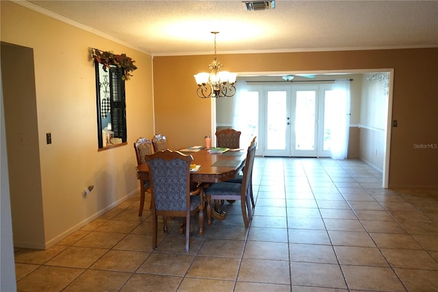 dining area with tile patterned floors, crown molding, french doors, and a chandelier