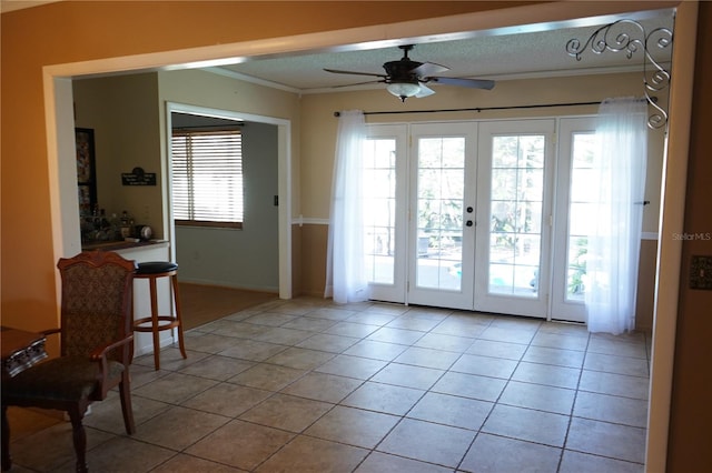 doorway to outside featuring french doors, a textured ceiling, ceiling fan, crown molding, and light tile patterned floors