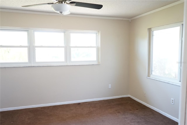 spare room featuring a textured ceiling, dark carpet, a wealth of natural light, and crown molding