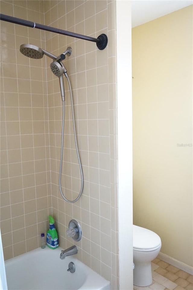 bathroom with tile patterned flooring, tiled shower / bath combo, and toilet