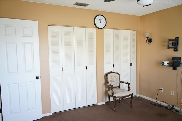 living area featuring ceiling fan, dark carpet, and a textured ceiling