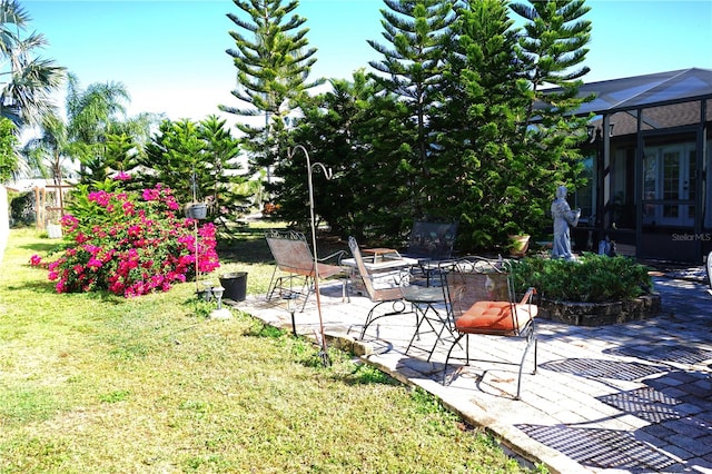 view of yard featuring glass enclosure, a patio area, and a fire pit