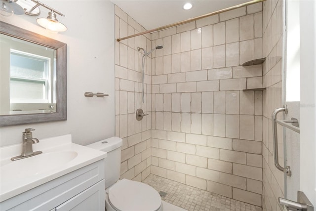 bathroom with a tile shower, vanity, and toilet