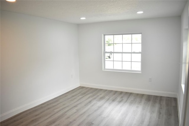 unfurnished room with a textured ceiling and light wood-type flooring