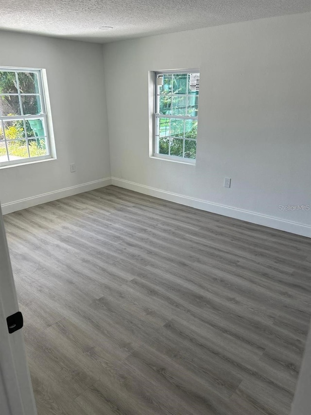 unfurnished room with dark wood-type flooring and a textured ceiling