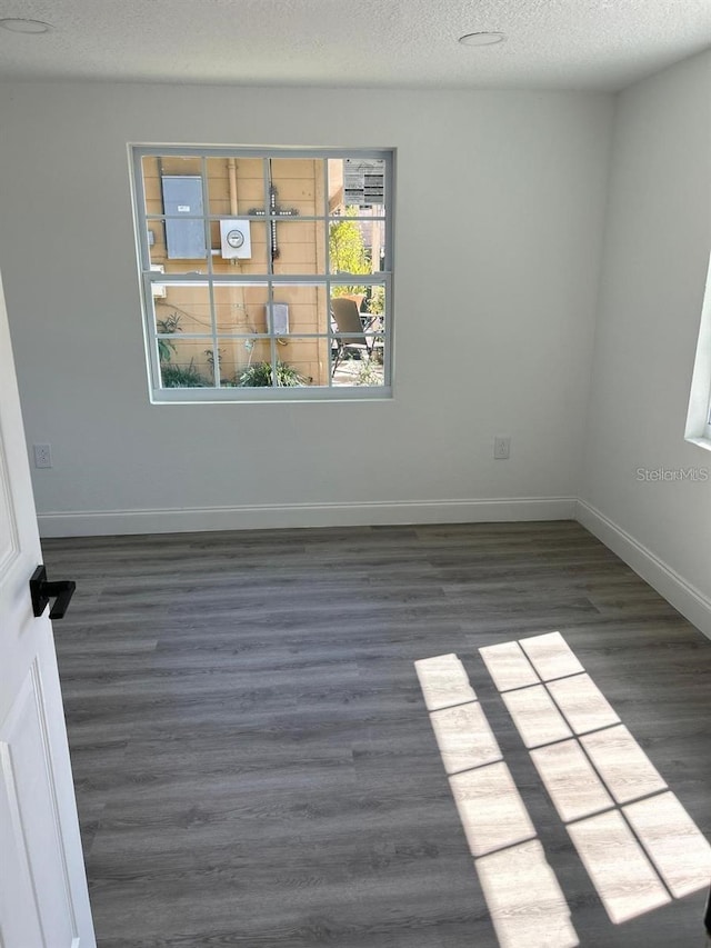 spare room with dark hardwood / wood-style flooring and a textured ceiling