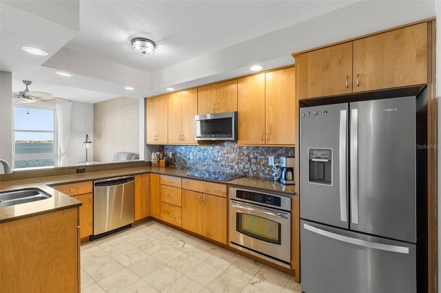 kitchen featuring decorative backsplash, appliances with stainless steel finishes, kitchen peninsula, ceiling fan, and sink