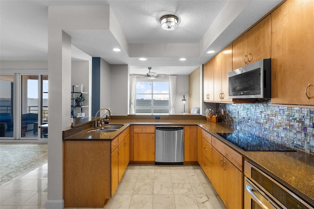 kitchen with ceiling fan, sink, stainless steel appliances, kitchen peninsula, and decorative backsplash