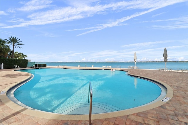 view of pool with a water view and a patio