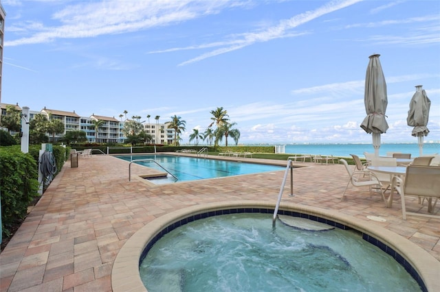 view of pool with a patio area, a community hot tub, and a water view