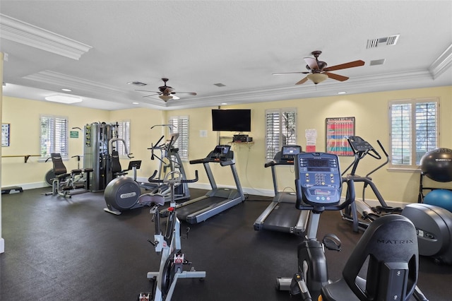 gym featuring a raised ceiling, ceiling fan, and ornamental molding