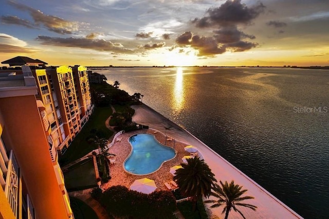 pool at dusk featuring a water view