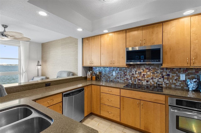 kitchen featuring decorative backsplash, sink, a water view, and appliances with stainless steel finishes