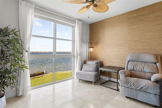 living area with a water view and ceiling fan