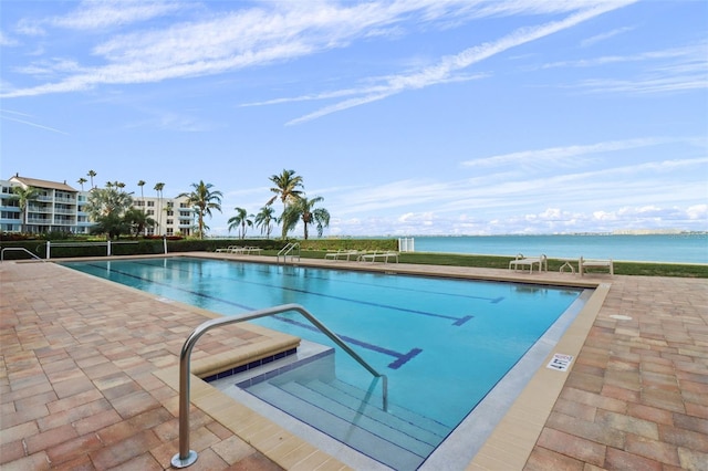 view of pool featuring a water view and a patio