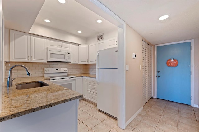 kitchen with white appliances, light stone counters, decorative backsplash, white cabinets, and sink