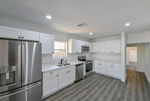 kitchen featuring sink, white cabinets, light wood-type flooring, and appliances with stainless steel finishes