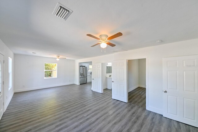 unfurnished living room with dark hardwood / wood-style flooring and ceiling fan