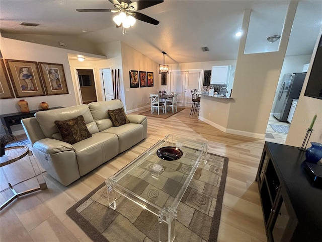 living room featuring ceiling fan with notable chandelier, light hardwood / wood-style flooring, and lofted ceiling