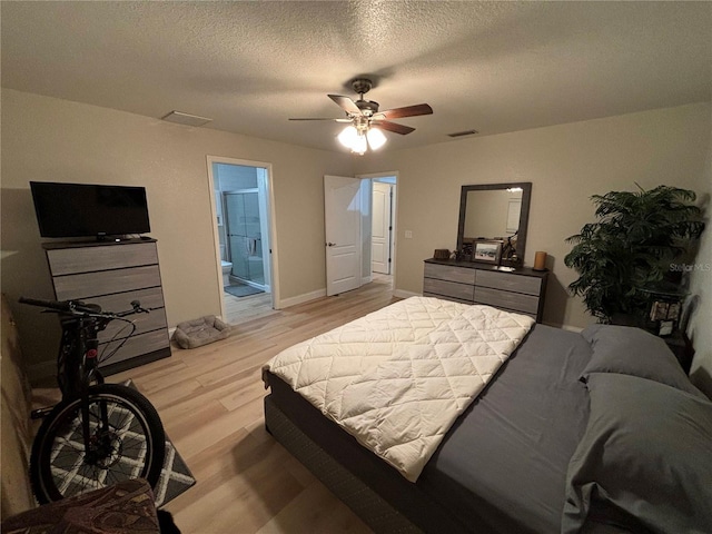 bedroom with ceiling fan, ensuite bathroom, a textured ceiling, and light wood-type flooring