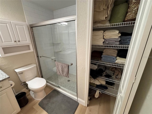 bathroom featuring toilet, vanity, wood-type flooring, and walk in shower