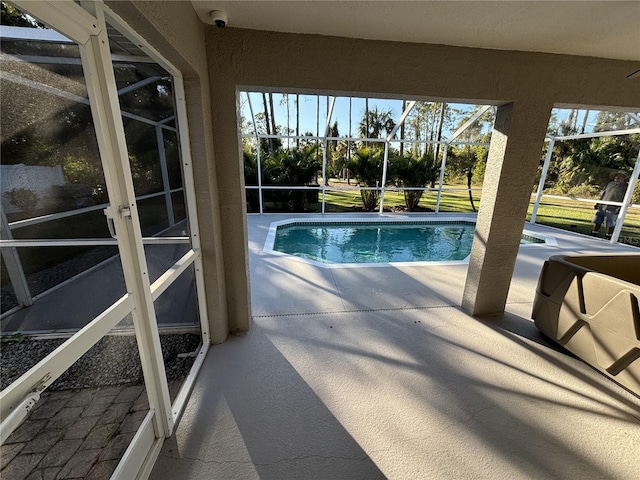 view of swimming pool featuring a patio and glass enclosure